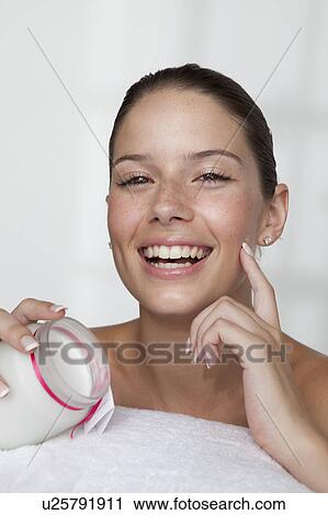 Stock Image - Woman rubbing moisturizer on her face. Fotosearch