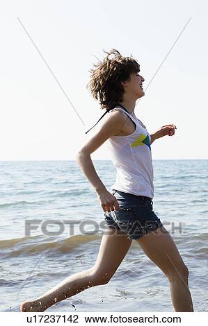 Woman running in waves on beach View Large Photo Image Stock Image - Woman running in waves on beach. Fotosearch