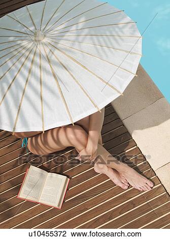 Woman sitting by pool under umbrella View Large Photo Image Stock Image - Woman sitting by pool under umbrella. Fotosearch