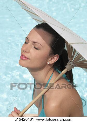 Woman sitting by pool under umbrella View Large Photo Image Stock Image - Woman sitting by pool under umbrella. Fotosearch