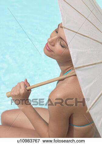 Woman sitting by pool under umbrella View Large Photo Image Stock Photo - Woman sitting by pool under umbrella. Fotosearch