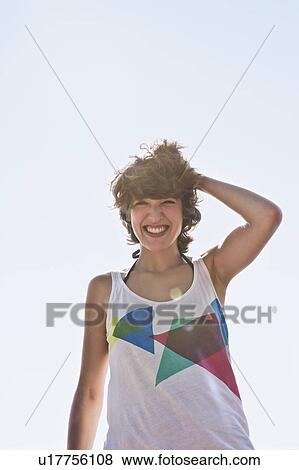Woman smiling against blue sky View Large Photo Image Stock Photo - Woman smiling against blue sky. Fotosearch