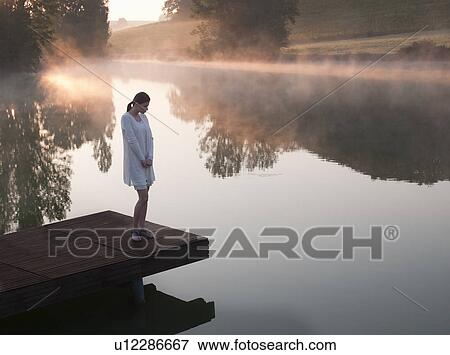 Woman standing on dock of lake View Large Photo Image Stock Photo - Woman standing on dock of lake. Fotosearch