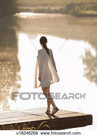Woman standing on dock of lake View Large Photo Image Stock Photo - Woman standing on dock of lake. Fotosearch