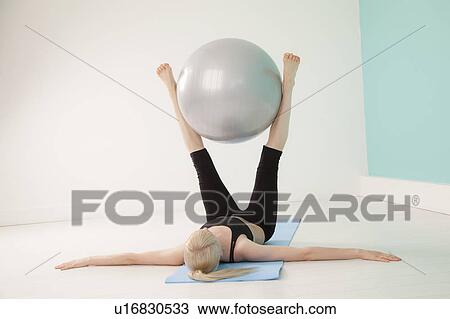 Stock Image - Woman using exercise ball. Fotosearch