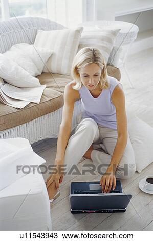 Woman using laptop in living room View Large Photo Image Stock Image - Woman using laptop in living room. Fotosearch