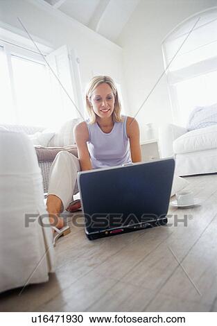 Woman using laptop in living room View Large Photo Image Stock Image - Woman using laptop in living room. Fotosearch