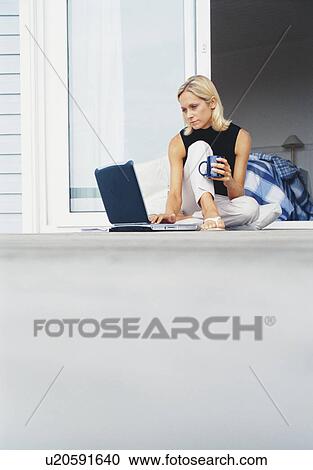 Stock Image - Woman using laptop on porch. Fotosearch