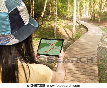 Stock Photography - Woman using tablet computer while hiking. Fotosearch