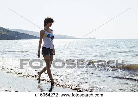Woman walking in waves on beach View Large Photo Image Stock Image - Woman walking in waves on beach. Fotosearch