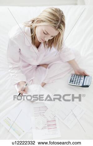 Stock Image - Woman working on bed. Fotosearch