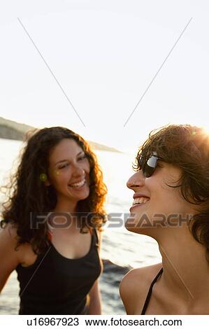 Stock Image - Women smiling on beach. Fotosearch