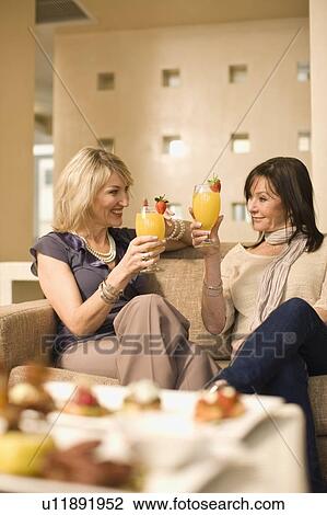 Women toasting each other in lounge View Large Photo Image Stock Image - Women toasting each other in lounge. Fotosearch