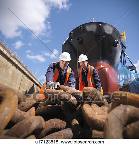 Stock Photography - Workers examining chain at shipyard. Fotosearch