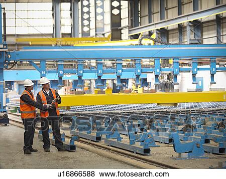 Stock Photo - Workers examining shipbuilding machinery. Fotosearch