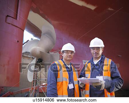 Stock Photograph - Workers standing on shipbuilding site. Fotosearch
