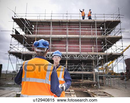 Stock Photography - Workers talking on shipbuilding site. Fotosearch