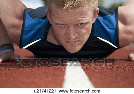 Stock Image - Athlete doing push ups on track. Fotosearch