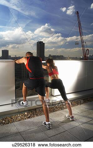 Stock Photo - Athletes exercising together on rooftop. Fotosearch
