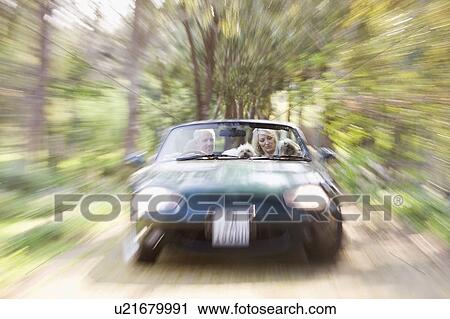 Stock Image - Blurred view of convertible on dirt path. Fotosearch