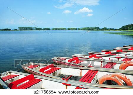 Picture - Boats docked by lake. Fotosearch