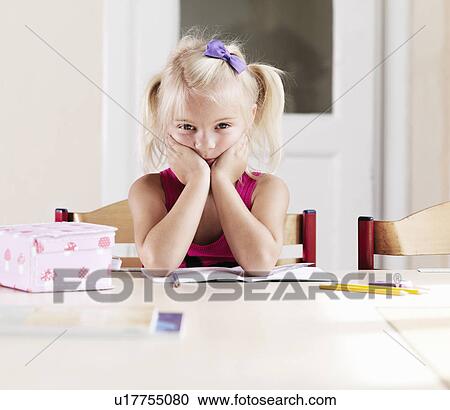 Stock Image - Bored girl doing homework at table. Fotosearch