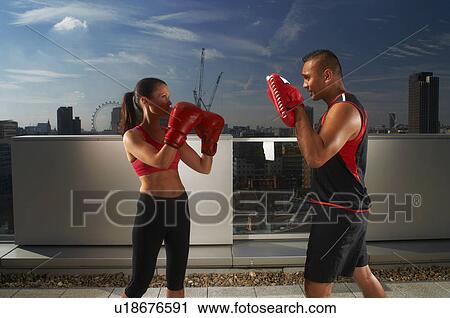 Stock Image - Boxer training with coach on rooftop. Fotosearch