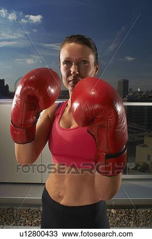 Stock Image - Boxer wearing gloves on urban rooftop. Fotosearch