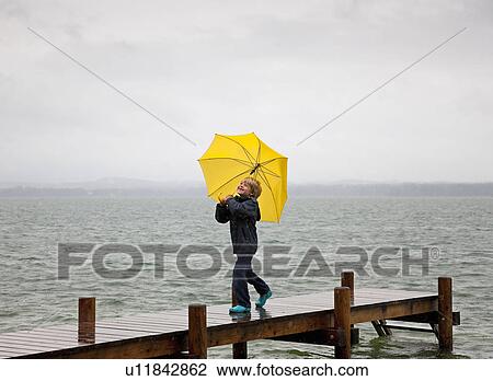 Boy carrying umbrella on wooden dock View Large Photo Image Stock Image - Boy carrying umbrella on wooden dock. Fotosearch