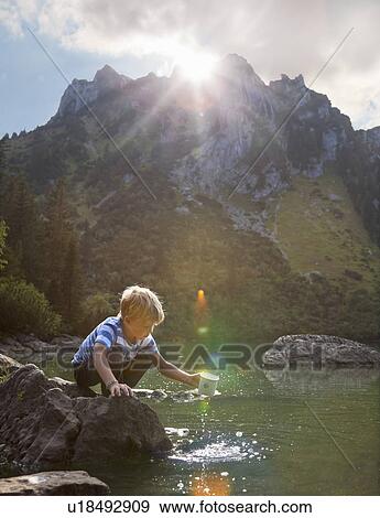 Boy dipping mug into still lake View Large Photo Image Stock Photo - Boy dipping mug into still lake. Fotosearch