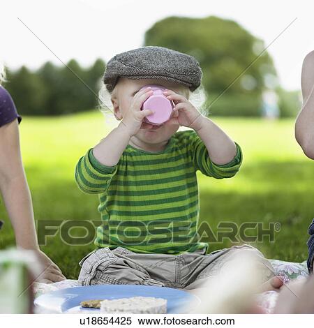 Stock Photography - Boy drinking from cup at picnic. Fotosearch