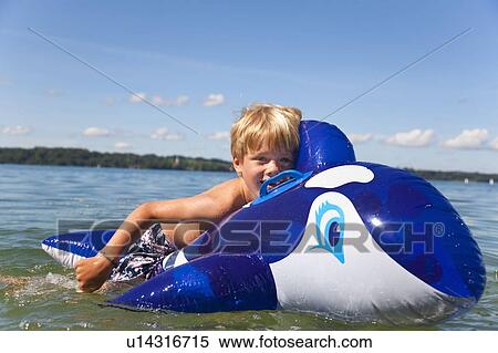 Boy floating in lake with toy whale View Large Photo Image Stock Photography - Boy floating in lake with toy whale. Fotosearch