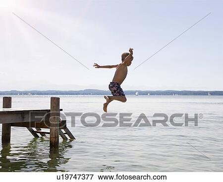 Boy jumping into lake from dock View Large Photo Image Stock Photo - Boy jumping into lake from dock. Fotosearch