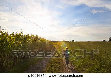 Picture - Boy playing on rural dirt path. Fotosearch
