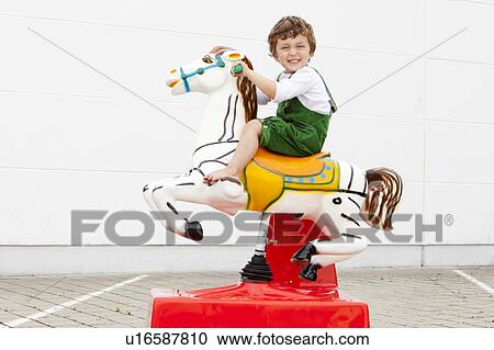 Boy riding mechanical horse outdoors View Large Photo Image Stock Image - Boy riding mechanical horse outdoors. Fotosearch