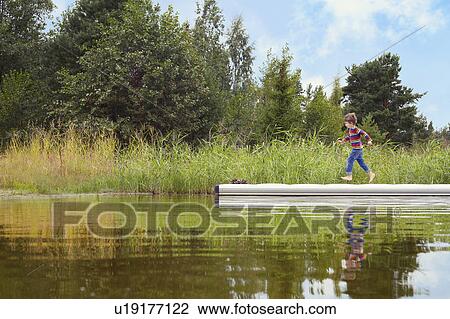 Stock Image - Boy running on wooden pier. Fotosearch