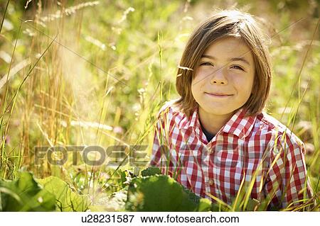 Stock Photo - Boy sitting in tall grass. Fotosearch