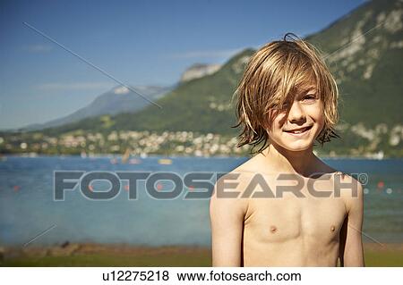 Boy smiling on shore of lake View Large Photo Image Stock Photo - Boy smiling on shore of lake. Fotosearch