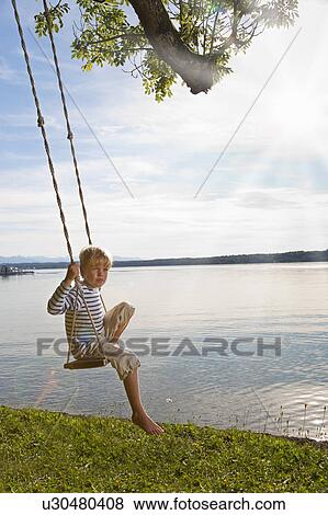 Boy swinging from tree by lake View Large Photo Image Stock Photo - Boy swinging from tree by lake. Fotosearch