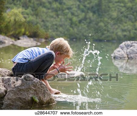 Stock Photo - Boy washing his face in still lake. Fotosearch