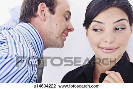 Stock Image - Business people whispering in office. Fotosearch