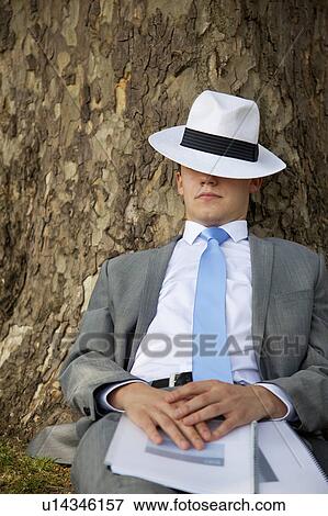 Stock Photo - Businessman napping on tree in park. Fotosearch