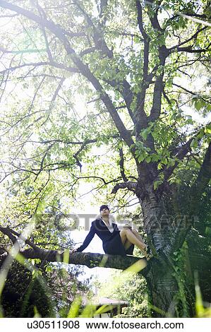 Stock Photo - Businesswoman sitting in tree. Fotosearch