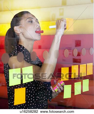 Businesswoman sticking notes on window View Large Photo Image Stock Image - Businesswoman sticking notes on window. Fotosearch