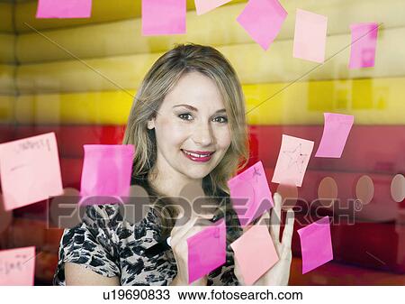 Businesswoman sticking notes on window View Large Photo Image Stock Image - Businesswoman sticking notes on window. Fotosearch