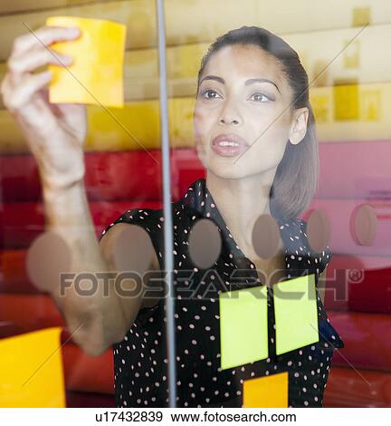 Businesswoman sticking notes on window View Large Photo Image Stock Photo - Businesswoman sticking notes on window. Fotosearch