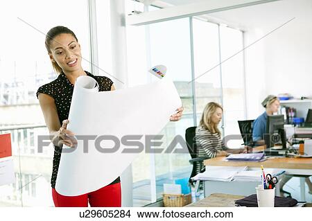 Businesswoman unrolling blueprint View Large Photo Image Picture - Businesswoman unrolling blueprint. Fotosearch