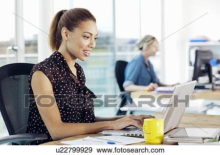 Businesswoman using laptop in office View Large Photo Image Stock Photo - Businesswoman using laptop in office. Fotosearch