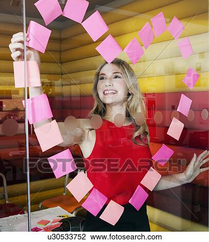 Stock Image - Businesswomen making heart with notes. Fotosearch