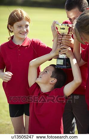 Stock Photo - Children cheering with trophy outdoors. Fotosearch